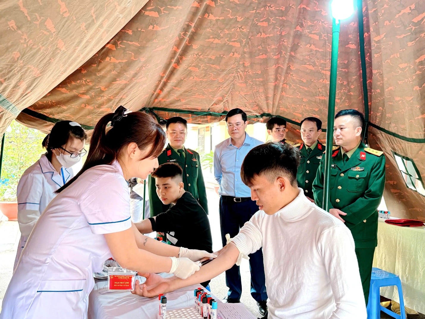 A nurse putting blood into a person's hand  Description automatically generated