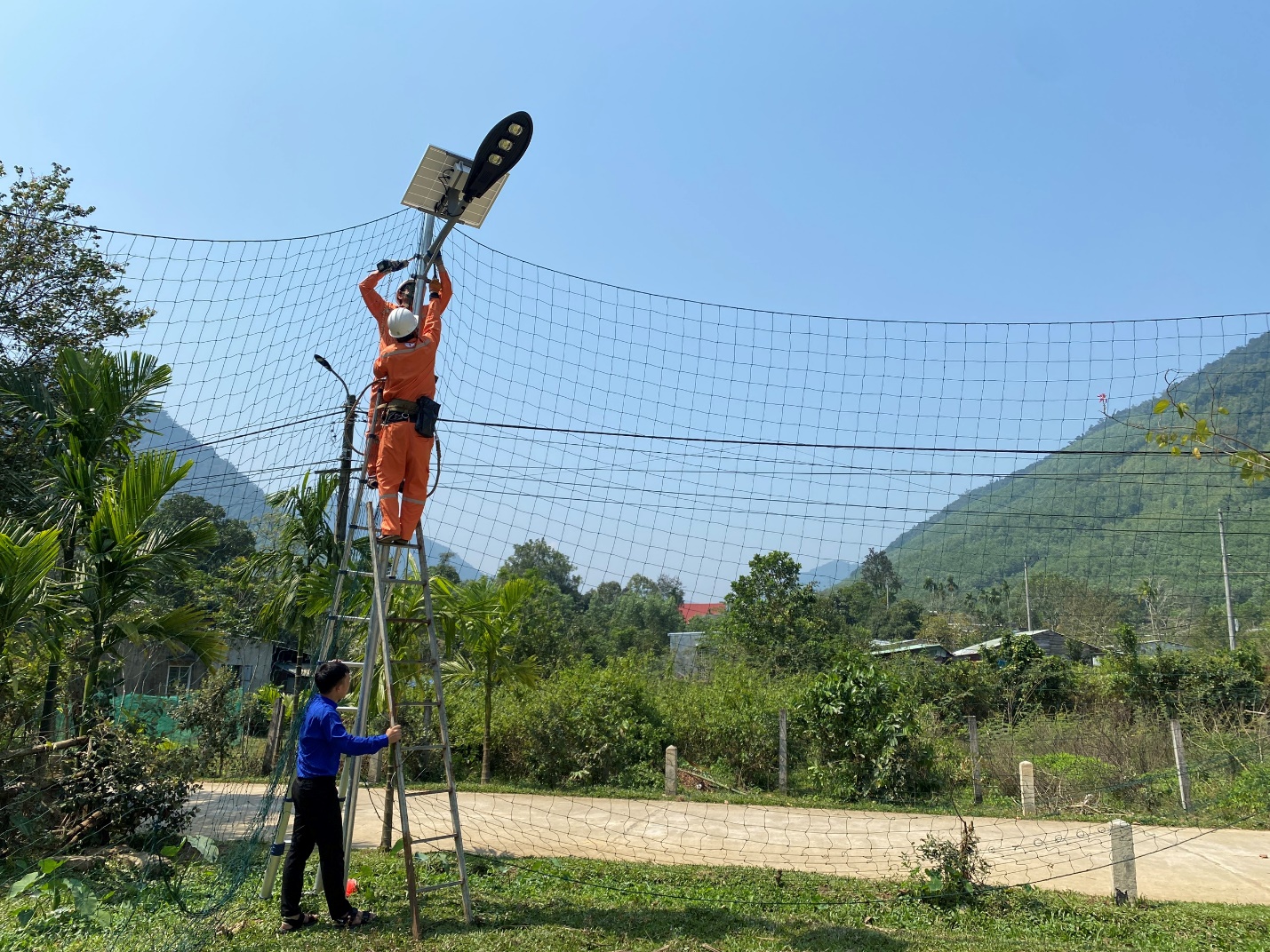 A person on a ladder with a lamp on top  Description automatically generated