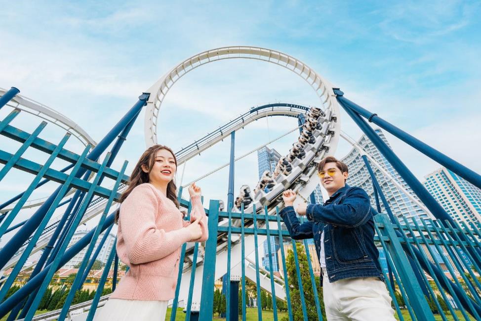 A person and person standing in front of a roller coaster  AI-generated content may be incorrect.