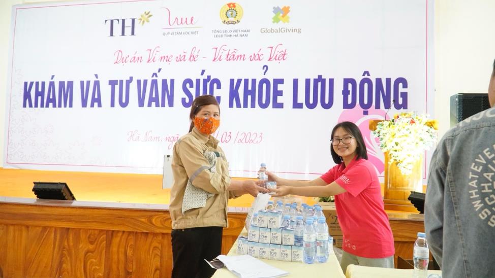 A couple of women standing next to a table with water bottles  AI-generated content may be incorrect.