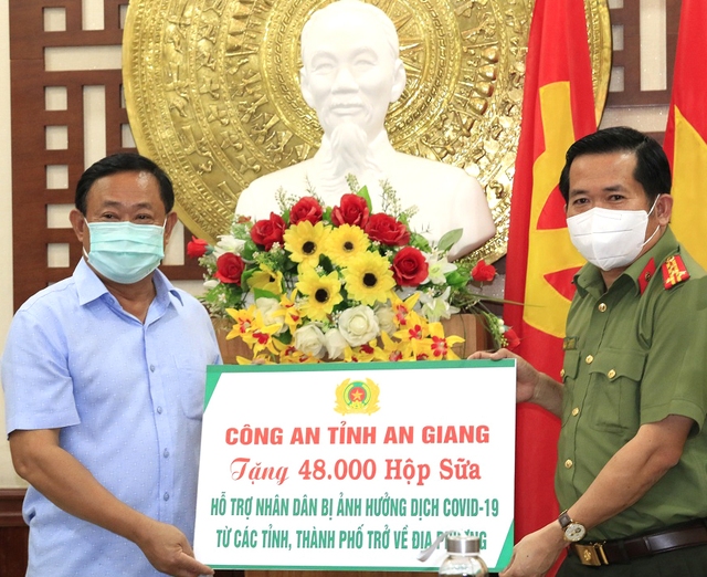 Đại tá Đinh Văn Nơi, Giám đốc Công an tỉnh An Giang trao bảng tượng trưng tặng 48.000 hộp sữa cho Chủ tịch Ủy ban MTTQ tỉnh - Nguyễn Tiếc Hùng.