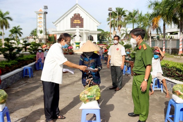 Trung tá Nguyễn Đức Hậu - Trưởng Công an TP Long Xuyên cùng Linh mục Trần Văn Khoa, Chánh xứ Giáo xứ Cần Xây tặng quà cho bà con giáo dân tại phường Bình Đức.