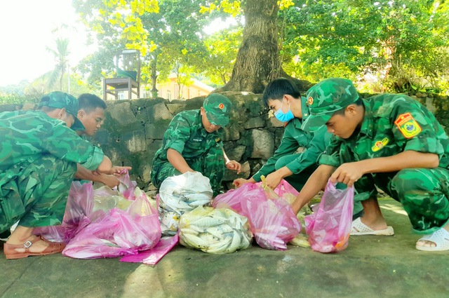 Cán bộ, chiến sỹ Đồn Biên phòng Thổ Châu chuẩn bị cá biển hỗ trợ người dân.