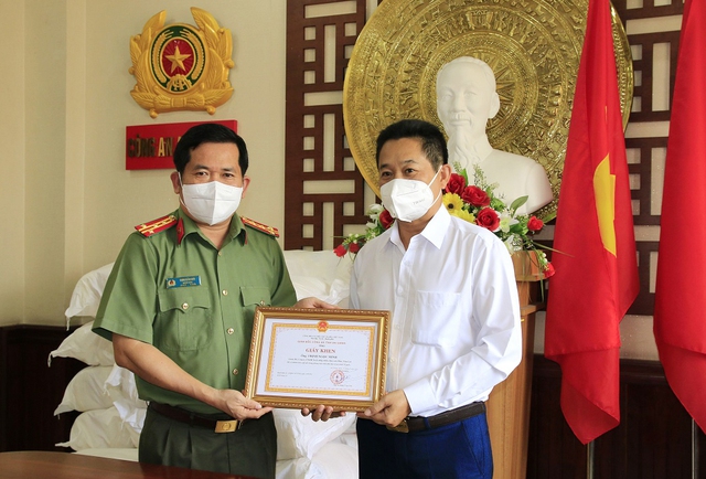 Đại tá Đinh Văn Nơi, Giám đốc Công an tỉnh trao Giấy khen cho ông Trịnh Ngọc Minh, Giám đốc Công ty TNHH Xuất nhập khẩu thủy sản Phúc Tâm Lợi.