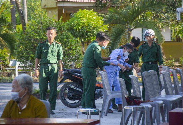 Cán bộ, chiến sĩ Đồn Biên phòng Cửa khẩu Giang Thành hỗ trợ người dân khó khăn trong đi lại đến điểm khám, cấp phát thuốc tại đơn vị.