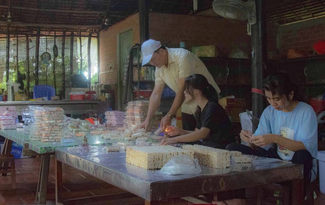 Phó Chủ tịch UBND huyện Long Hồ, Võ Trung Sơn xem người dân làm thành phẩm bánh cốm.