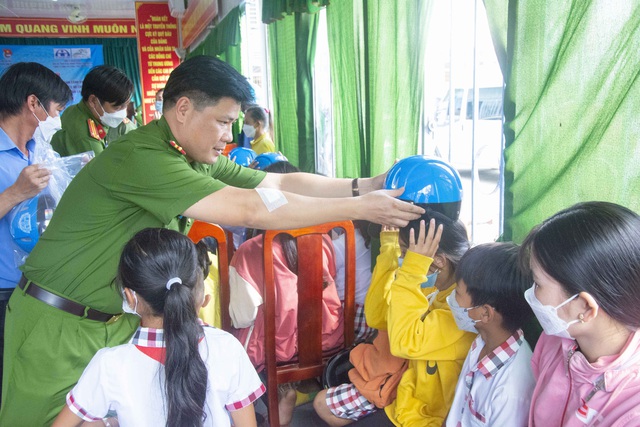 Trung tá Trương Thanh Mộng - Phó Trưởng phòng Cảnh sát Kinh tế, Công an TP Cần Thơ tặng nón bảo hiểm cho các em học sinh.