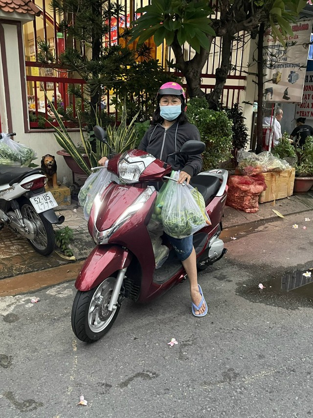 Thanh Hường (ngồi trên xe máy) đi gửi thực phẩm cho các hộ dân
