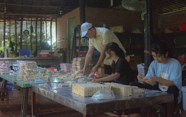 Phó Chủ tịch UBND huyện Long Hồ, Võ Trung Sơn xem người dân làm thành phẩm bánh cốm.