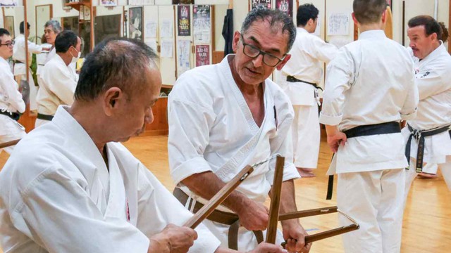 Du khách người Úc Alex Mitrakis (giữa) đã đến thăm một võ đường ở Okinawa để luyện tập với các loại vũ khí truyền thống, chẳng hạn như &quot;côn nhị khúc&quot;. (Ảnh của Tomoyoshi Oshikiri)