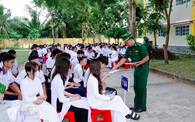 Cán bộ đồn Biên phòng trung Bình cấp phát tờ rơi tuyên truyền cho các em học sinh.