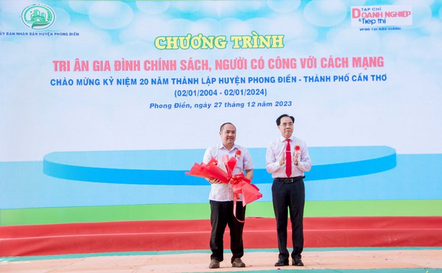Ông Đào Ngọc Chi, Bí thư Huyện ủy Phong Điền tặng hoa cho ông Nguyễn Hồng Ân, Trưởng VPĐD Tạp chí Doanh nghiệp và Tiếp thị tại Hậu Giang.