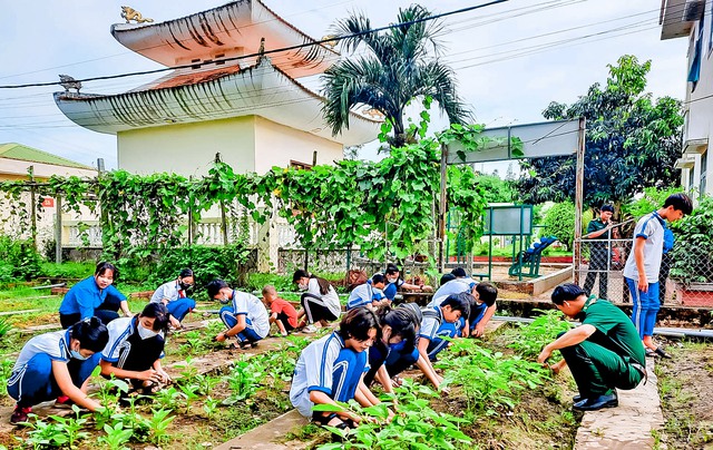 Các em học sinh cần mẫn chăm sóc rau xanh tại khu vực tăng gia của Đồn Biên phòng cửa khẩu quốc tế Vĩnh Xương.