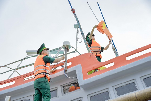 Cán bộ trạm Kiểm soát Biên phòng Dương Đông, kiểm tra thiết bị giám sát hành trì và treo mới cờ Tổ quốc trên tàu cá ngư dân địa phương.