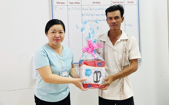 Bà Nguyễn Thị Ngọc Mai, Phó Chủ tịch UBND xã Bình Minh, huyện Vĩnh Thuận tặng quà cho anh Nguyễn Thanh Tuấn.