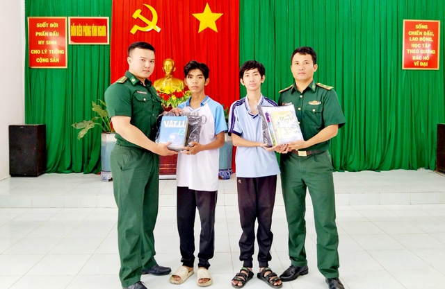 Cán bộ Đồn Biên phòng Vĩnh Nguơn tặng quà cho 2 em học sinh trong Chương trình Nâng bước em tới trường.