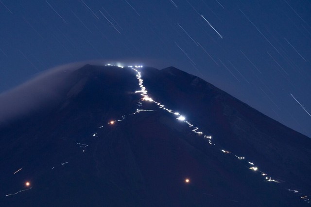 Những ngọn đèn do những người đi bộ mang theo nhằm ngắm bình minh từ đỉnh núi sẽ chiếu sáng những con đường mòn trên Núi Phú Sĩ vào ban đêm.