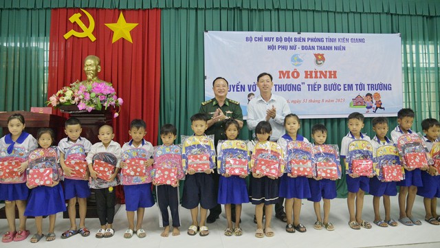 Đại diện Phòng chính trị BĐBP Kiên Giang và lãnh đạo UBND xã Phú Lợi trao quà cho các em học sinh nghèo tại điểm Trường Tiểu học Phú Lợi.
