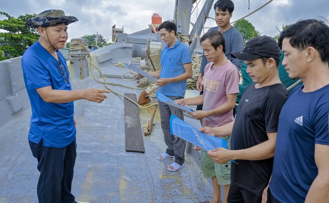 Anh Bùi Tấn Lượng phát tờ rơi, tuyên truyền về chống khai thác IUU đến ngư dân địa phương.