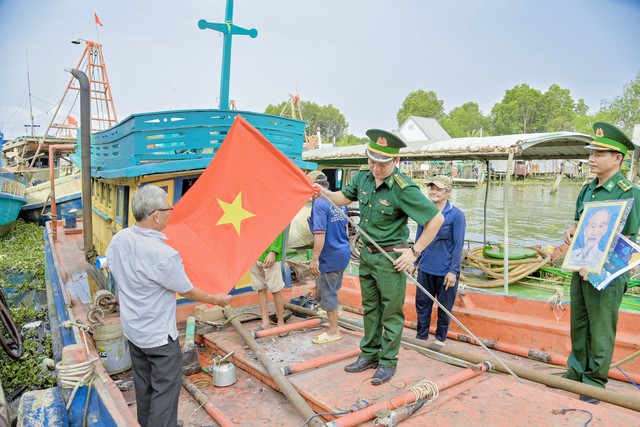 Tổ công tác đồn Biên phòng Lình Huỳnh, tặng cờ, ảnh Bác cho ngư dân trước lúc ra khơi đánh bắt.