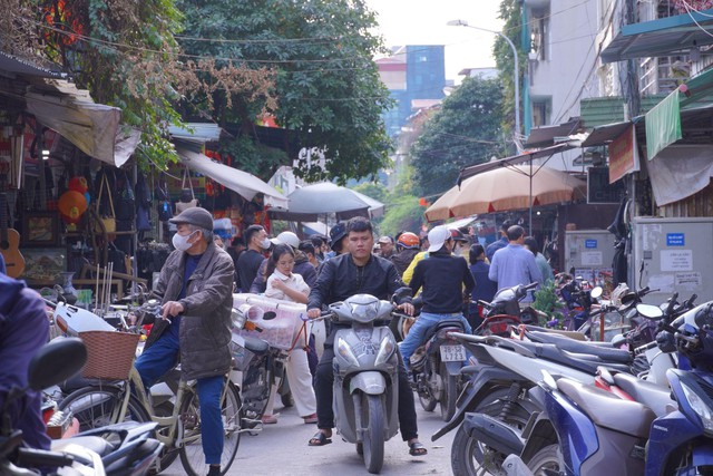 Lối vào chợ luôn nhộn nhịp với dòng người ra vào, xe máy dựng kín hai bên, tạo nên không gian đặc trưng của một khu chợ đô thị.